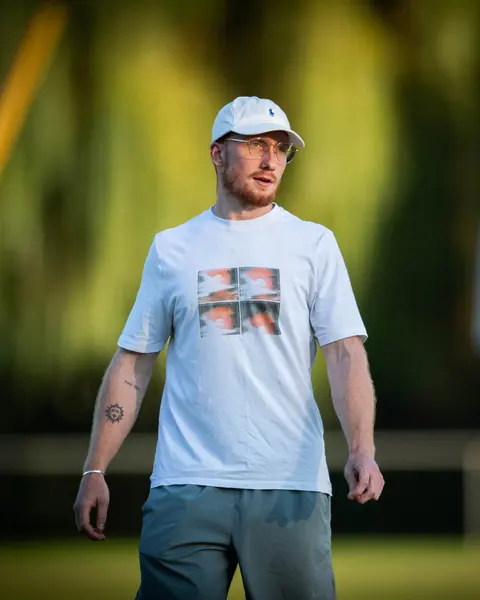 Jahen Garçaut, casquette blanche, en train de coacher sur un terrain